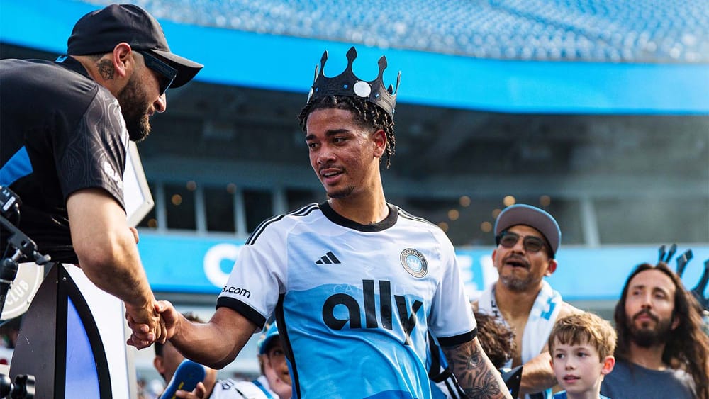 Idan Toklomati of Charlotte FC wearing a crown and shaking hands with a fan after a match