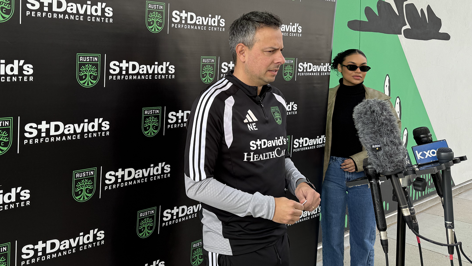 Austin FC head coach Nico Estévez at press event standing in front of microphones